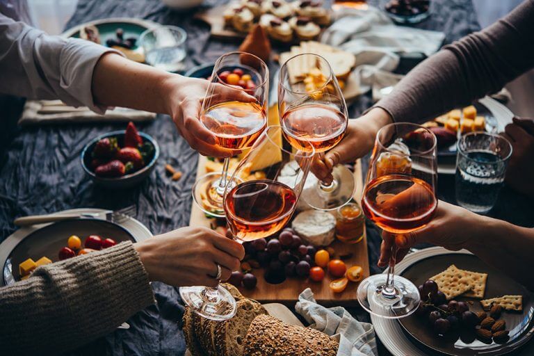 Menschen stoßen mit Wein an, Käsebrett im Hintergrund - Käserei Woerle