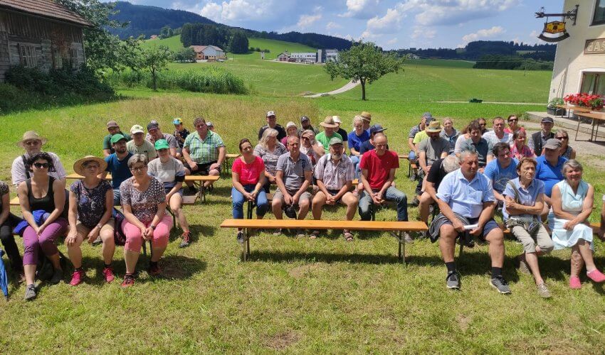 Bauernhofspaziergang mit Leuten, die auf einer Bank sitzen und einem Vortrag lauschen – Käserei Woerle