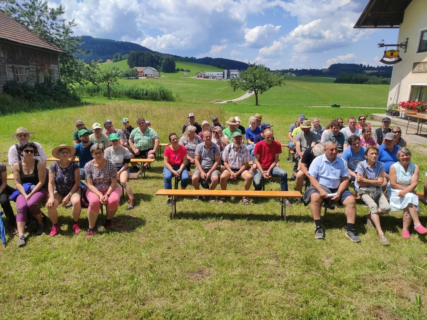 Bauernhofspaziergang mit Leuten, die auf einer Bank sitzen und einem Vortrag lauschen – Käserei Woerle