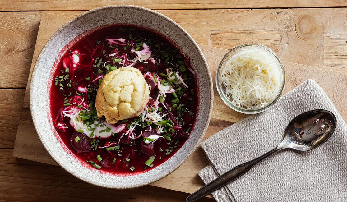 Borschtsch mit einem Knödel auf der Suppe und Kren daneben von oben fotografiert